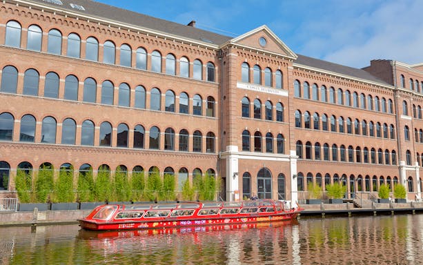 Hop On Hop Off boat near Coster Diamonds building in Amsterdam canal.