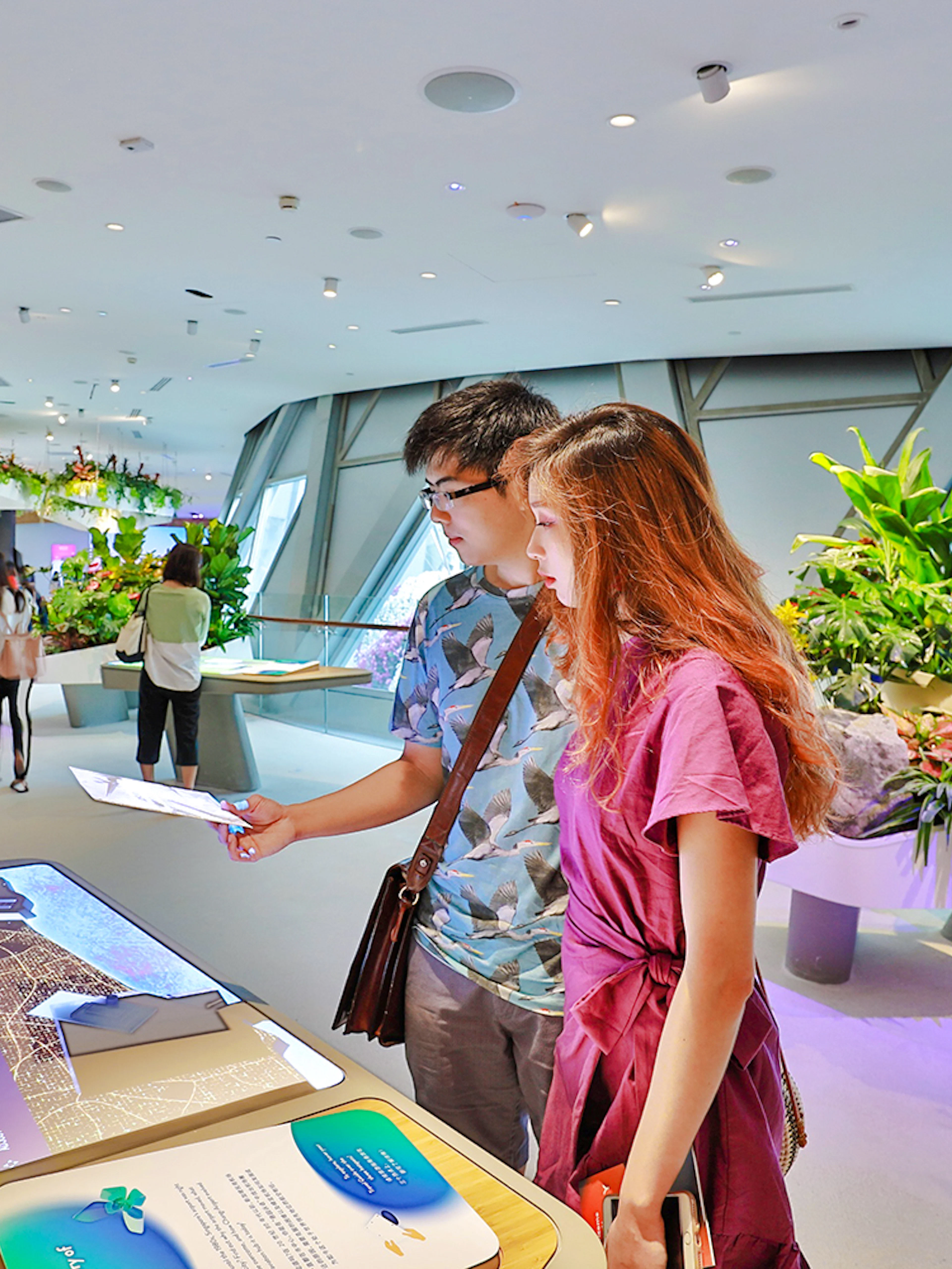 Visitors engaging with interactive displays at Changi Experience Studio, surrounded by hanging gardens.