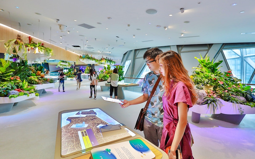 Visitors engaging with interactive displays at Changi Experience Studio, surrounded by hanging gardens.