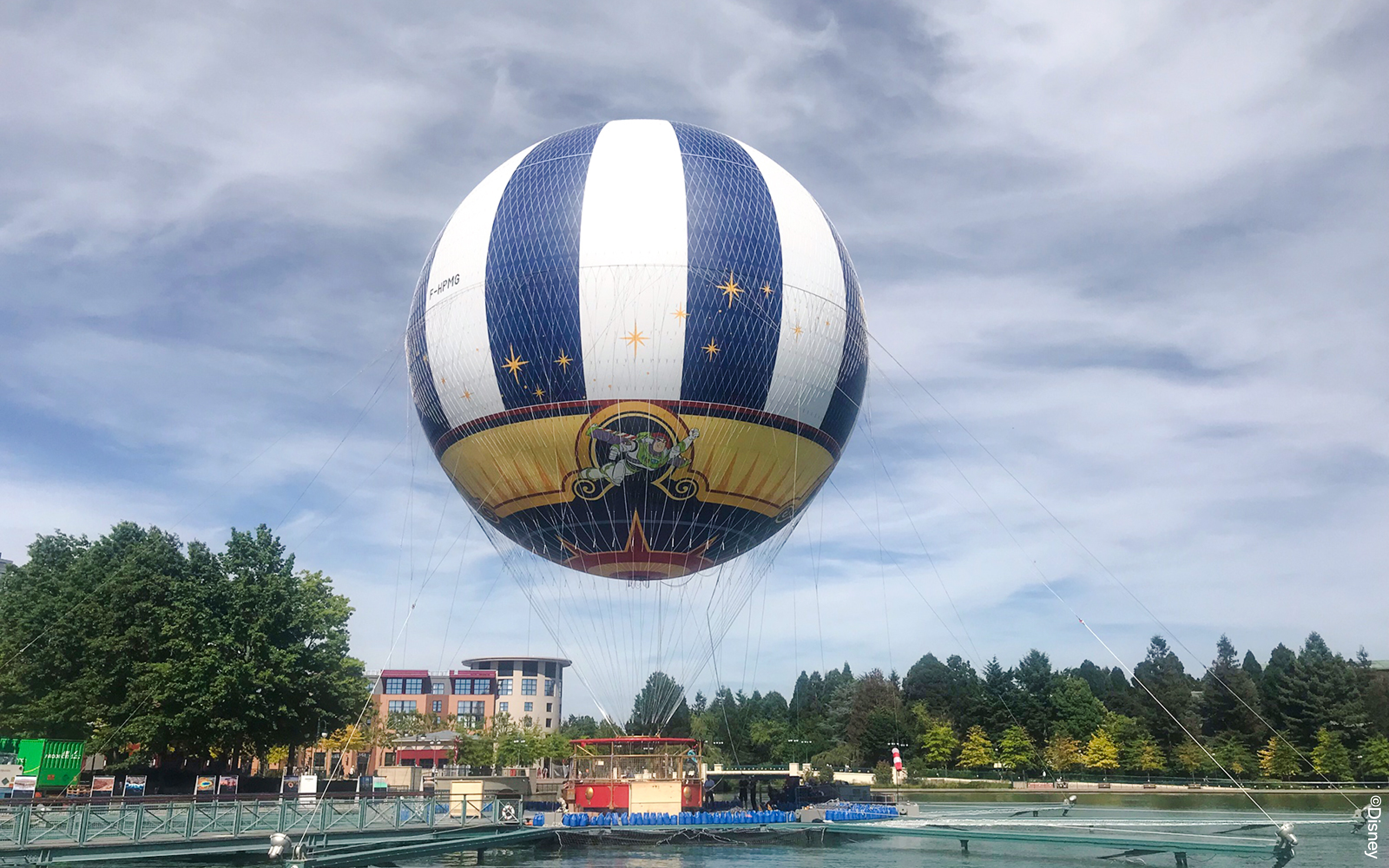 Balloon PanoraMagique floating at Disneyland Paris, France with trees and buildings in the background.