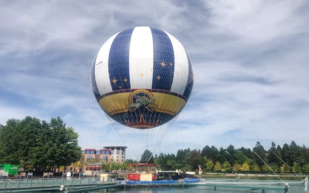 Balloon PanoraMagique floating at Disneyland Paris, France with trees and buildings in the background.