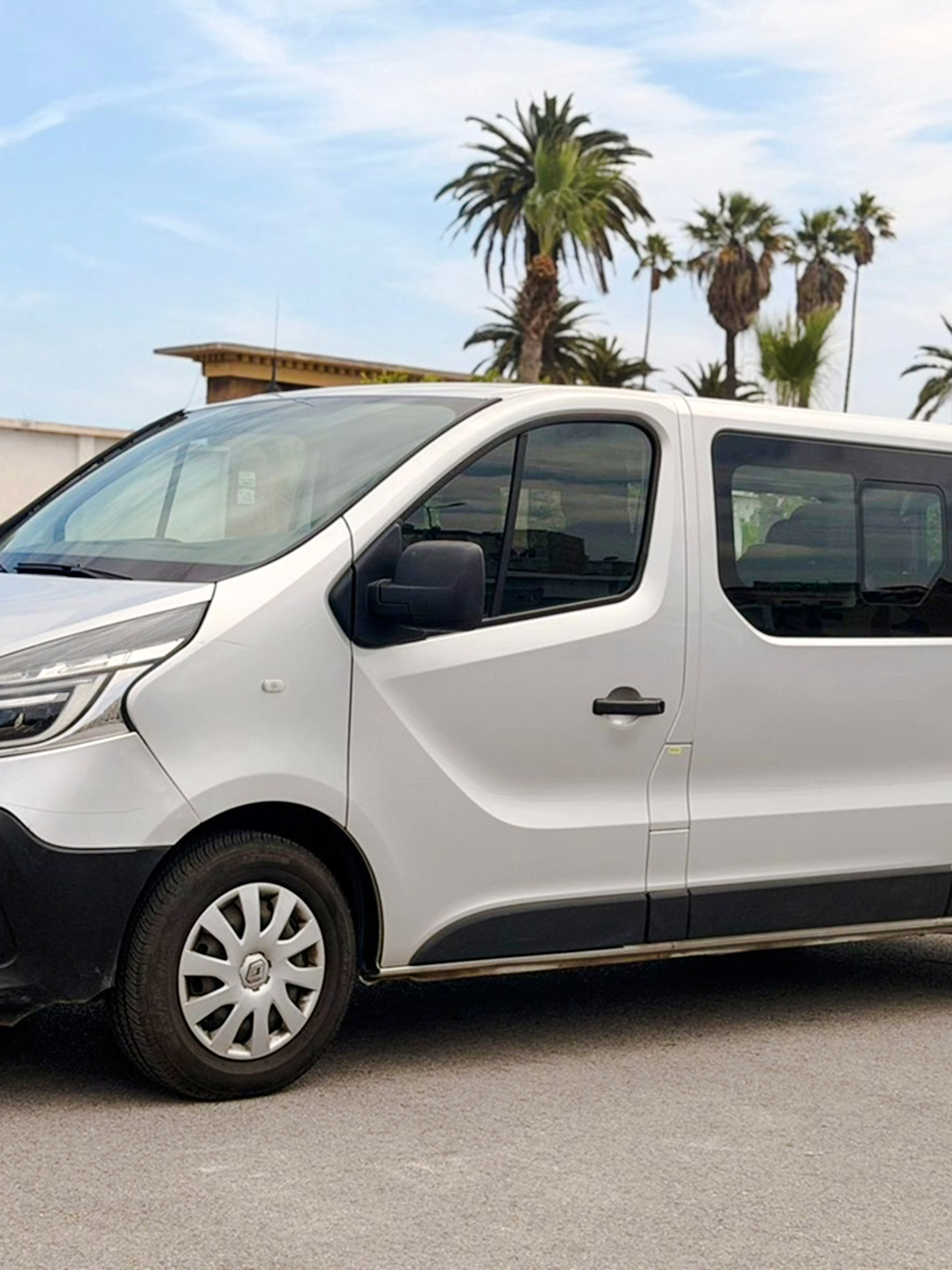 Minivan for airport transfers in Marrakech, parked with palm trees in the background.