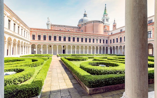 Borges Labyrinth in Venice courtyard with manicured hedges and historic architecture.