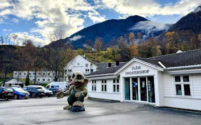 Troll statue outside Flåm Sweater Shop with mountains in the background.