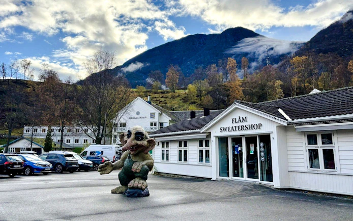 Troll statue outside Flåm Sweater Shop with mountains in the background.