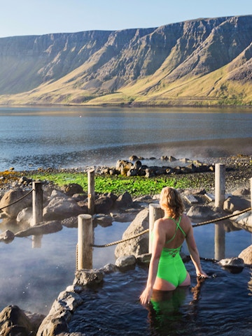 Person enjoying Hvammsvik Hot Spring with scenic mountain backdrop in Iceland.