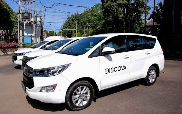 White minivans for shared airport transfers to Ngurah Rai International Airport, Bali.