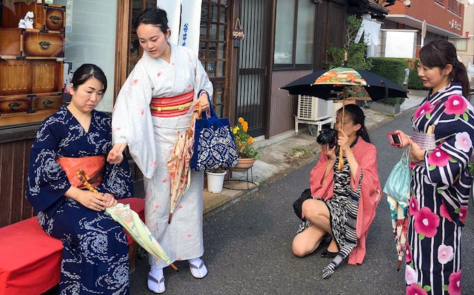 Women in traditional kimonos during a cultural experience in Japan, one holding a camera.