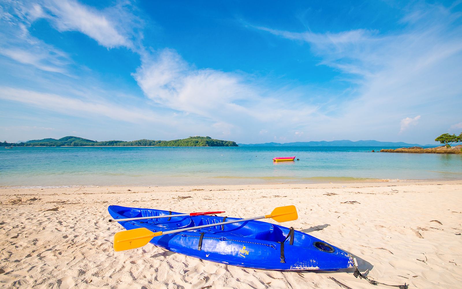 Blue kayaks on the sandy shore of Koh Naka Noi Beach, Phuket, with Naka Island in the background.