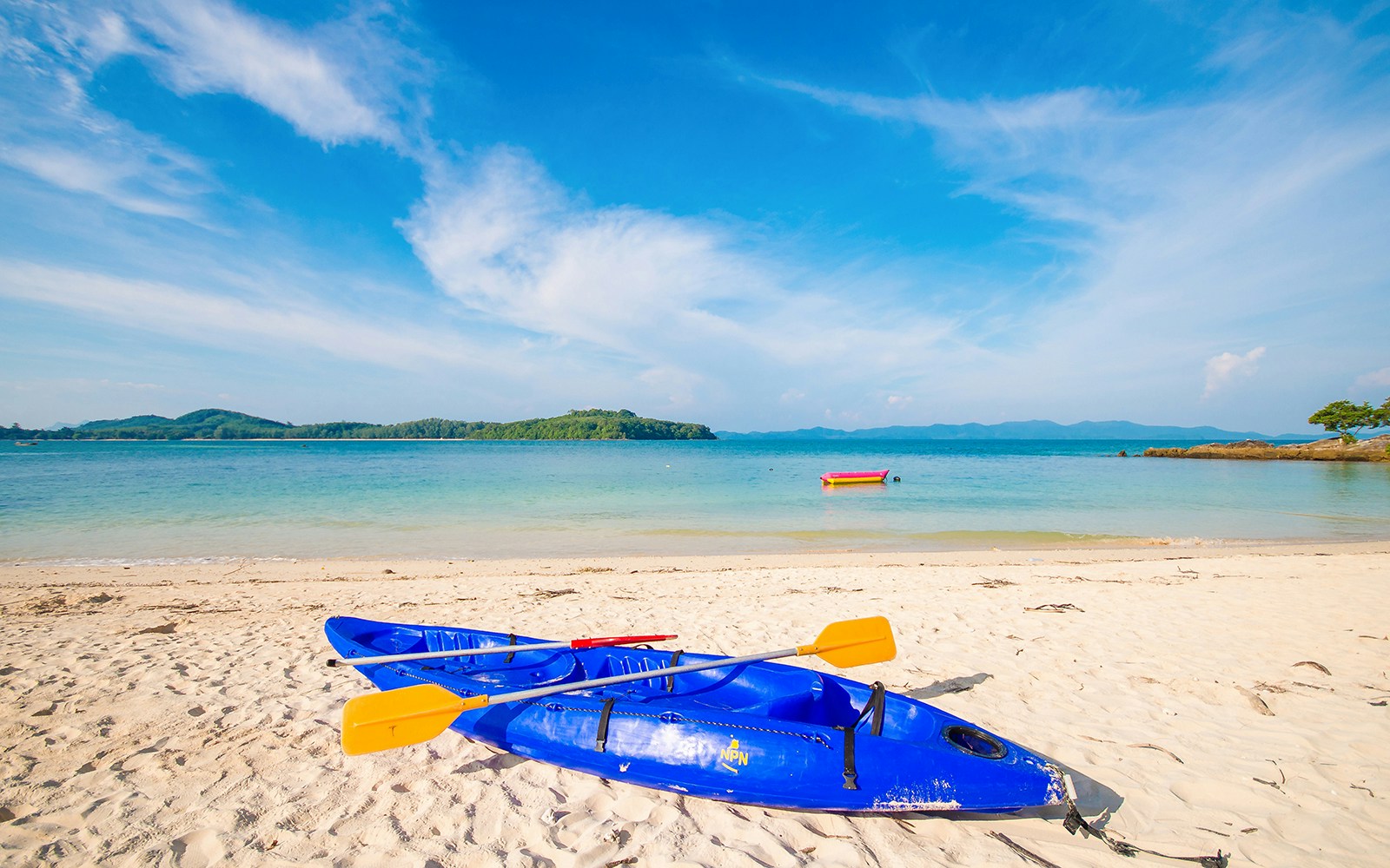 Blue kayaks on the sandy shore of Koh Naka Noi Beach, Phuket, with Naka Island in the background.