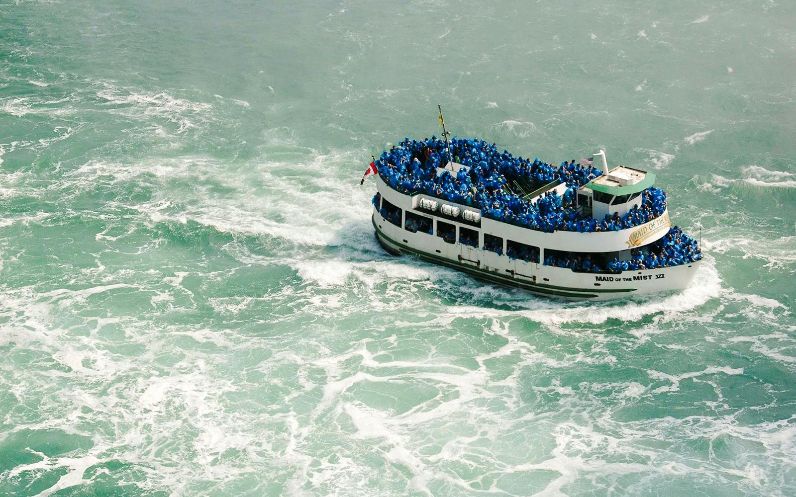 Boat tour at Niagara Falls USA with passengers in blue raincoats.