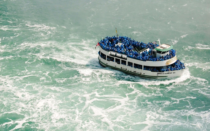 Boat tour at Niagara Falls USA with passengers in blue raincoats.