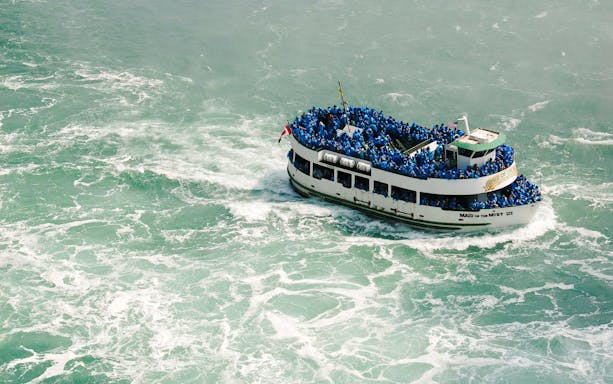 Boat tour at Niagara Falls USA with passengers in blue raincoats.