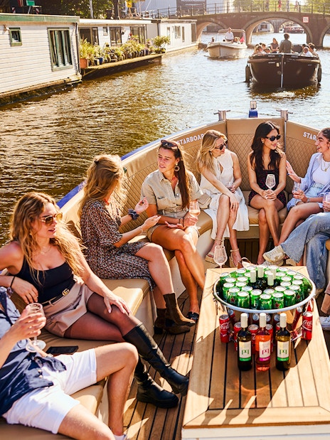 Guests enjoying drinks on a luxury canal cruise in Amsterdam.