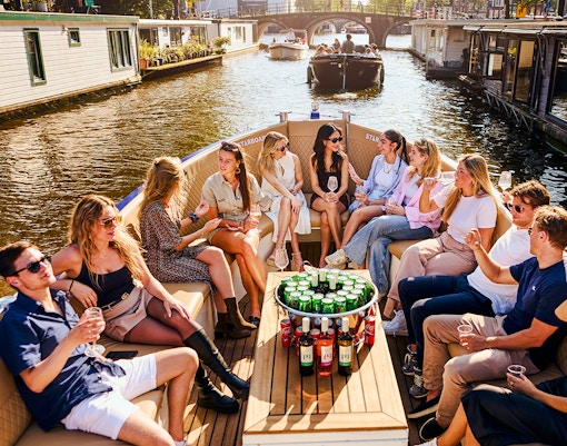 Guests enjoying drinks on a luxury canal cruise in Amsterdam.