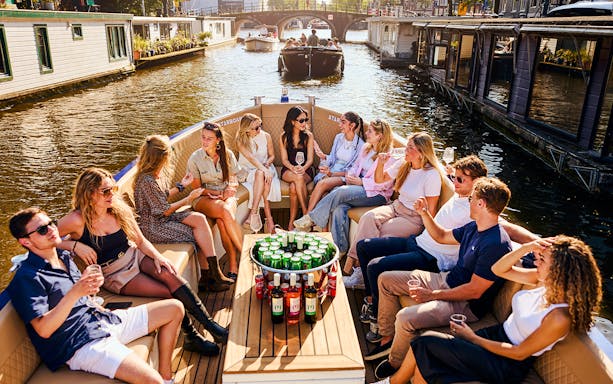 Guests enjoying drinks on a luxury canal cruise in Amsterdam.