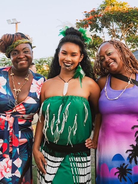 Guests with a Polynesian woman in traditional attire at Mauka Warriors Luau.