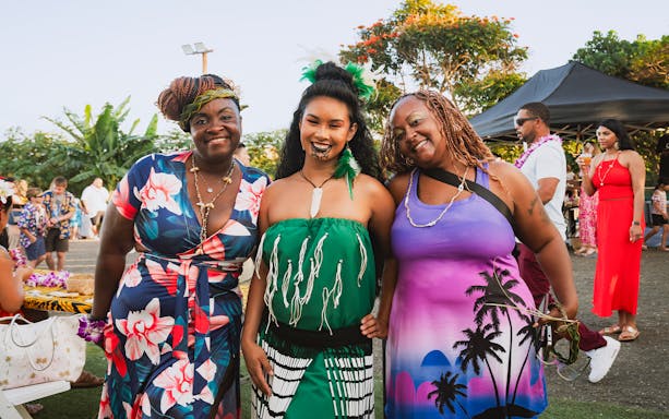 Guests with Polynesian woman in traditional attire and kākau at Mauka Warriors Luau, Hawaii.