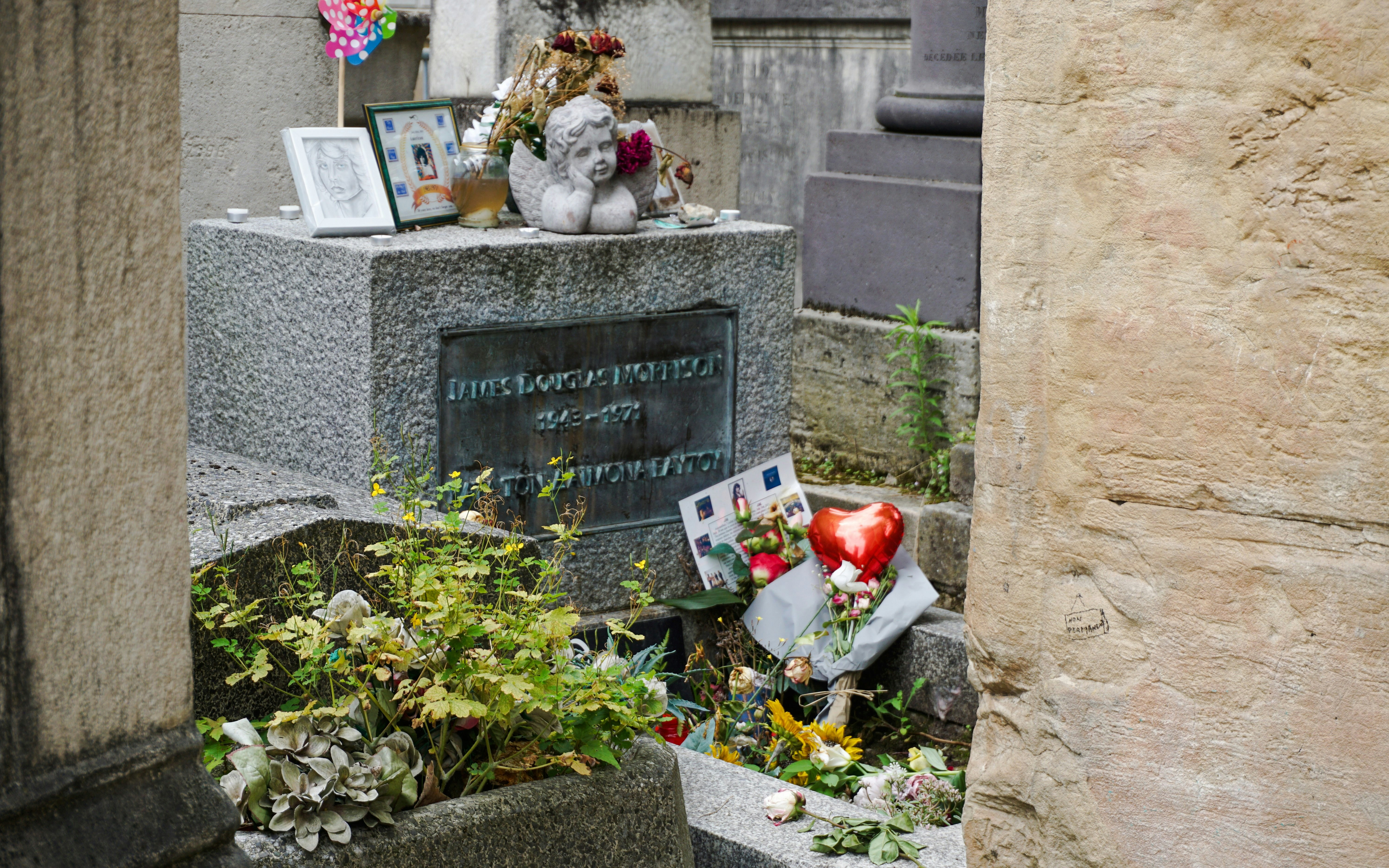 Jim Morrison's grave with flowers and tributes at Père Lachaise Cemetery, Paris.