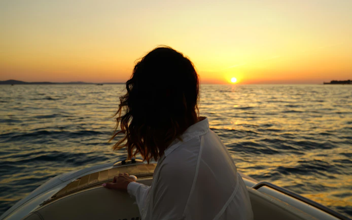 Person on a boat enjoying a sunset cruise near Zadar with sparkling wine.