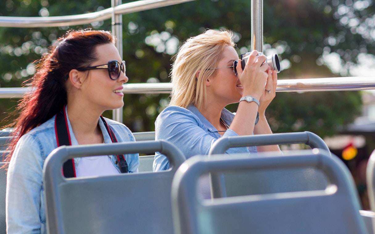 Tourists on Madrid Hop-On Hop-Off bus, capturing photos near Santiago Bernabéu Stadium.