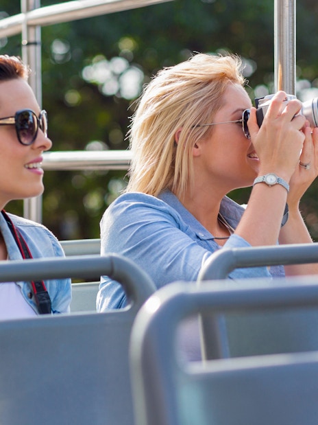 Tourists on Madrid Hop-On Hop-Off bus, capturing photos near Santiago Bernabéu Stadium.