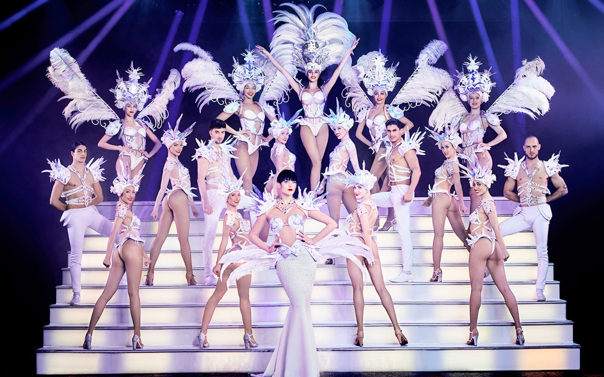 Cabaret performers in elaborate costumes on stage, Paris New Year's Eve show.