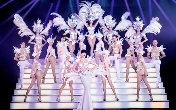 Cabaret performers in elaborate costumes on stage, Paris New Year's Eve show.