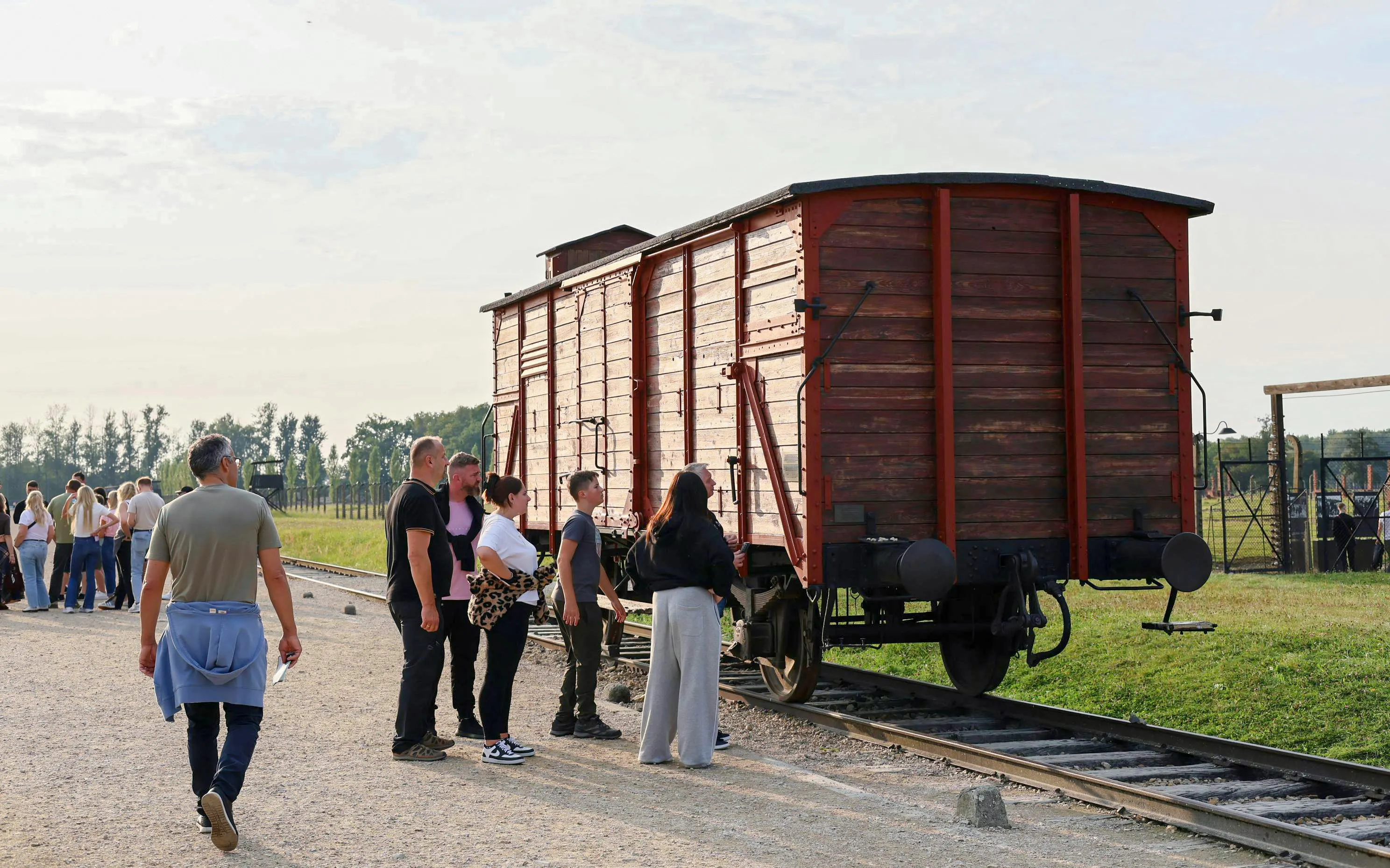Visitors observing a historic train car at Auschwitz-Birkenau during a guided tour from Krakow.