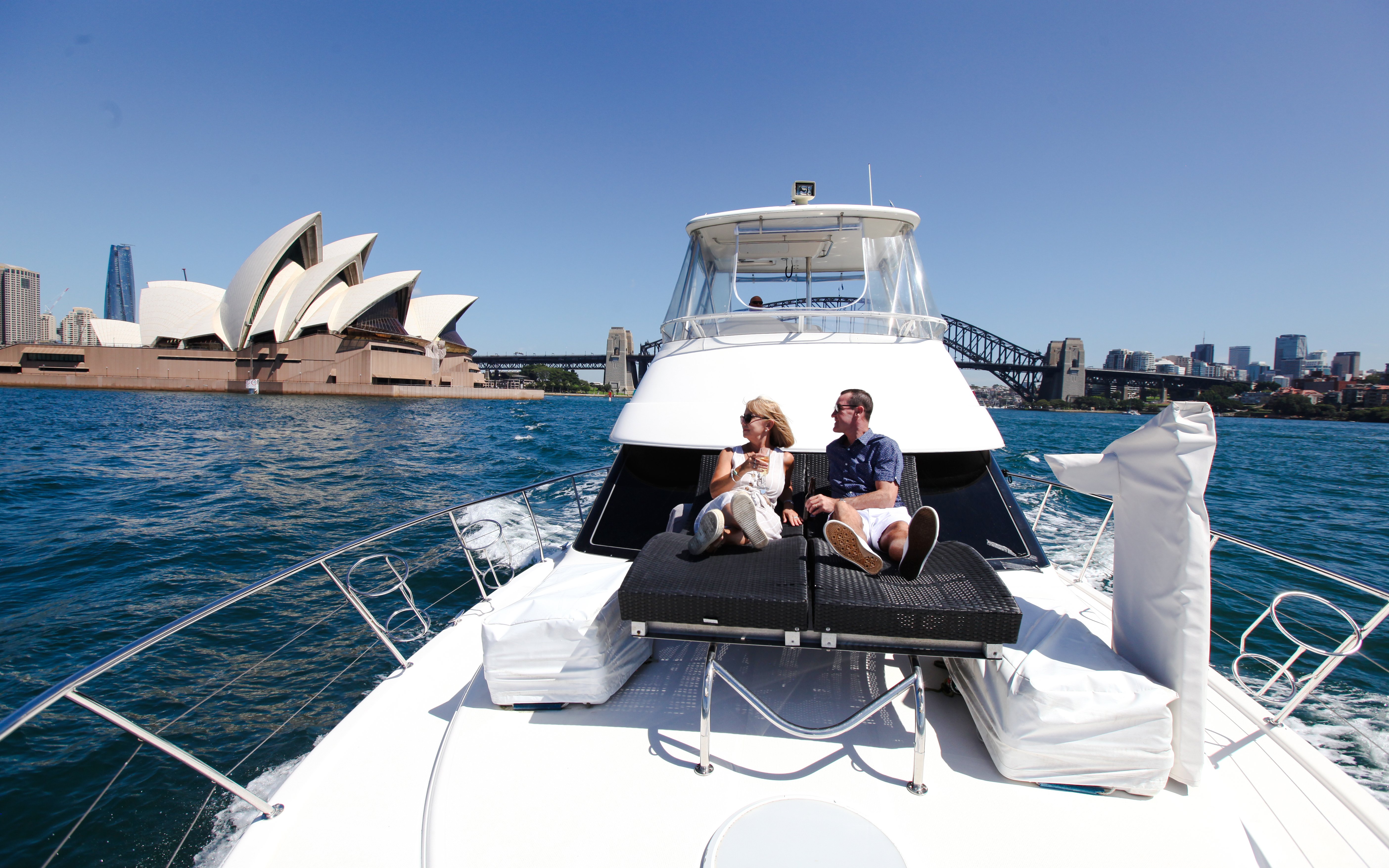 Couple relaxing on a boat with Sydney Opera House and Harbour Bridge in the background.