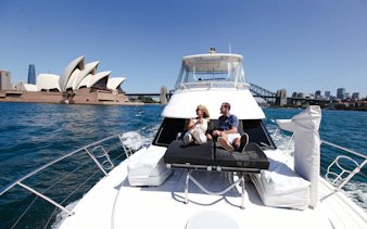 Couple relaxing on a boat with Sydney Opera House and Harbour Bridge in the background.