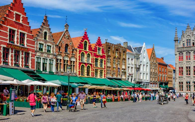 Colorful historic buildings and people in Market Square, Bruges.