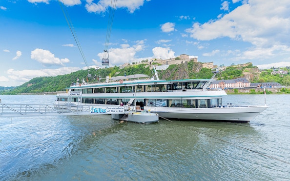 Koblenz sightseeing cruise boat on the Rhine River with Ehrenbreitstein Fortress in the background.