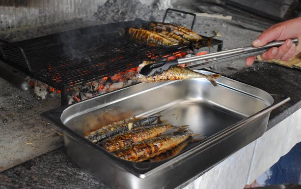 Grilled fish being prepared on an open flame during Blue Lagoon and 3 Island tour from Split.
