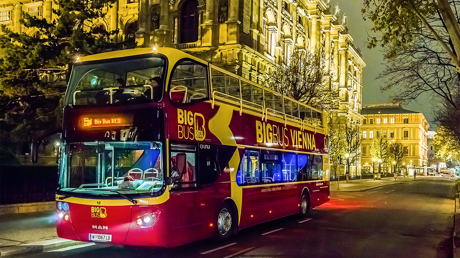 Vienna Big Bus Tour with a view of historic buildings and city streets at night.