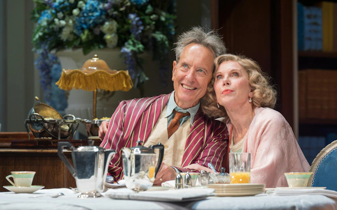 Actors in a scene from "Hay Fever" at West End, seated at a dining table with tea set.
