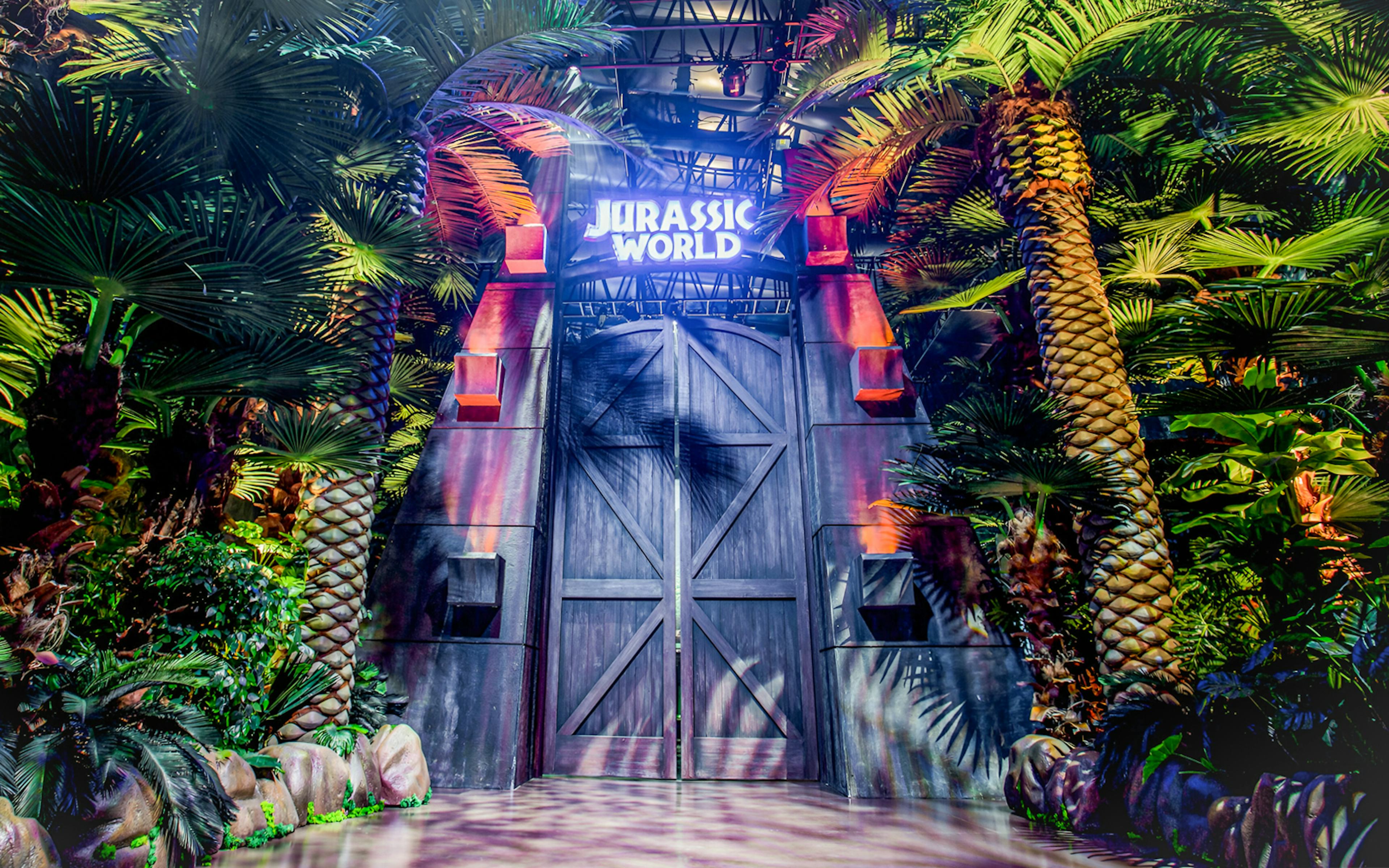 Entrance to Jurassic World: The Exhibition surrounded by lush greenery in Melbourne.
