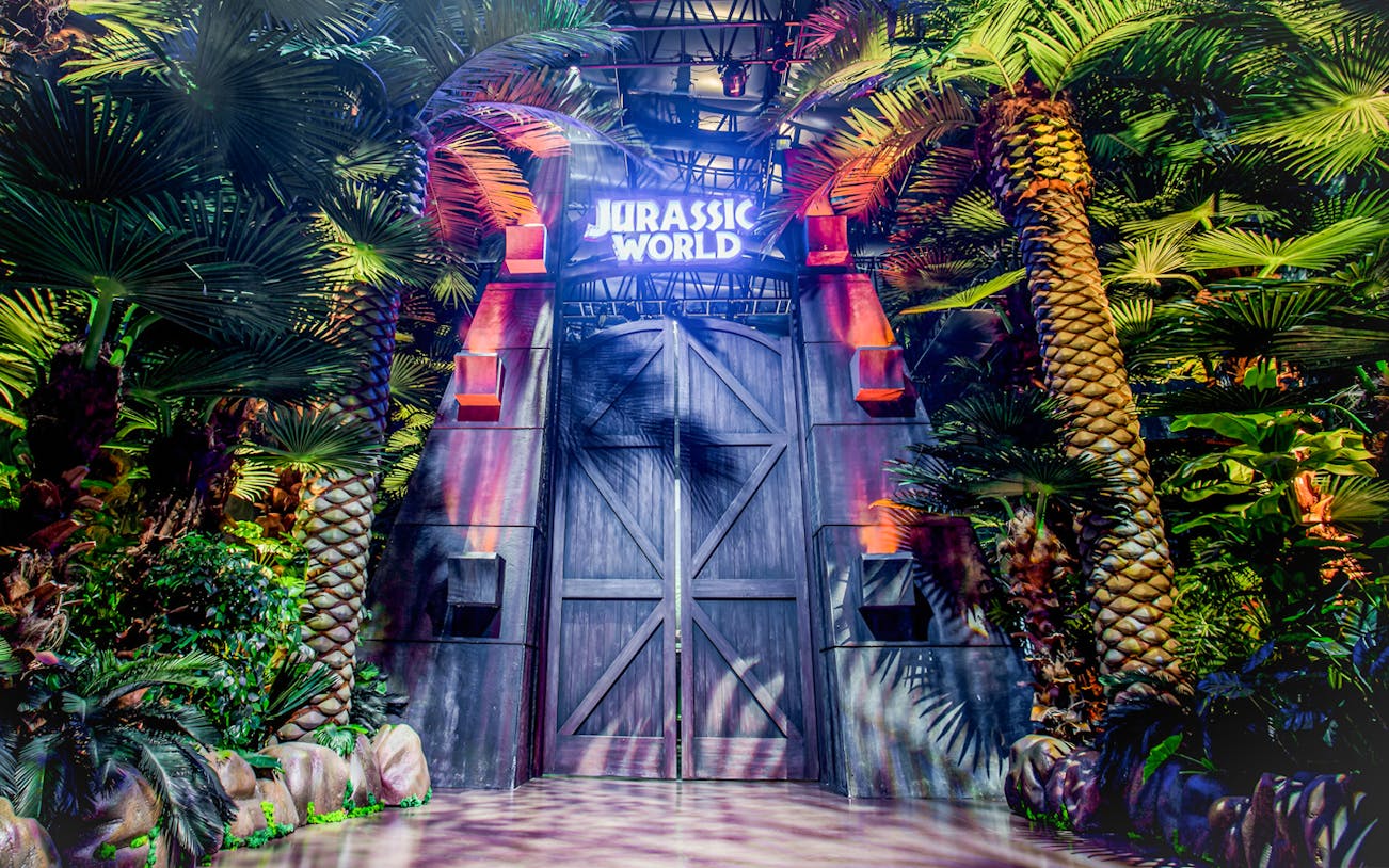 Entrance to Jurassic World: The Exhibition surrounded by lush greenery in Melbourne.