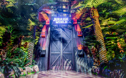 Entrance to Jurassic World: The Exhibition surrounded by lush greenery in Melbourne.