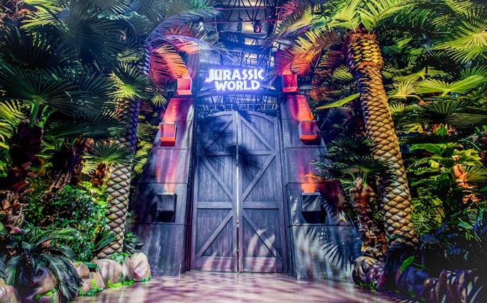 Entrance to Jurassic World: The Exhibition surrounded by lush greenery in Melbourne.