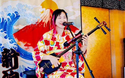Singer playing shamisen on Traditional Yakatabune Cruise with Mount Fuji backdrop.