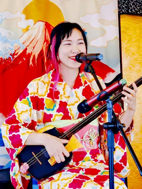 Singer playing shamisen on Traditional Yakatabune Cruise with Mount Fuji backdrop.