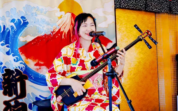 Singer playing shamisen on Traditional Yakatabune Cruise with Mount Fuji backdrop.