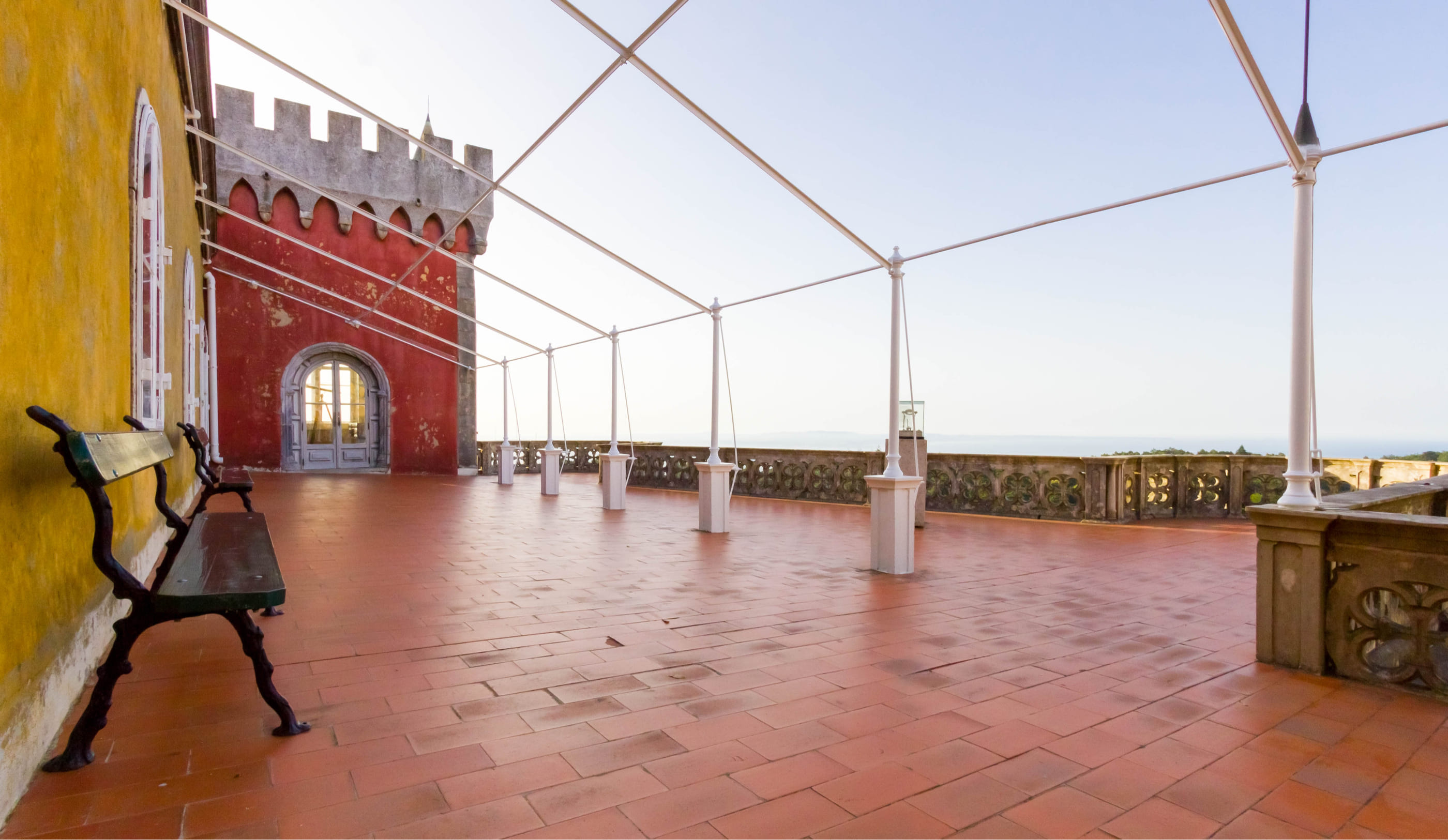 Queen's terrace at Pena Palace with red and yellow walls, overlooking scenic views.