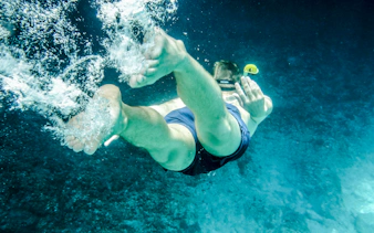 Snorkeler diving in clear waters of Mnemba Island Atoll, Zanzibar.