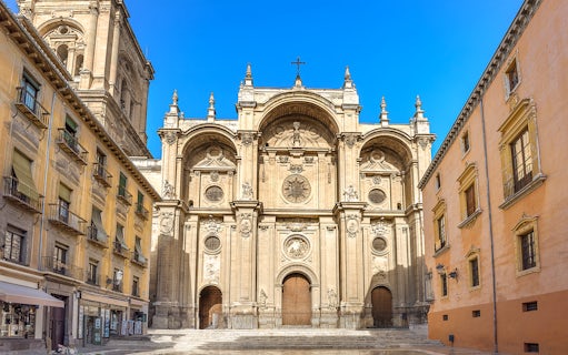 Granada Cathedral entrance with ornate facade and surrounding historic buildings.