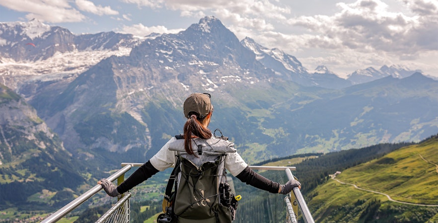 Traveler on a viewing platform overlooking the Swiss Alps with a Swiss Travel Pass.