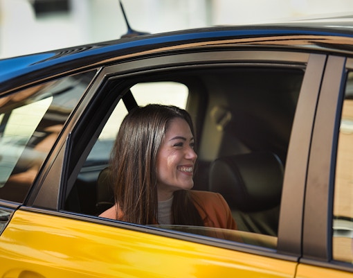 Passenger smiling in a taxi for Charles de Gaulle Airport private transfer.
