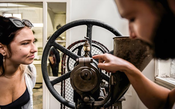 Tourists examining historical machinery during a pharmacy cellar tour.
