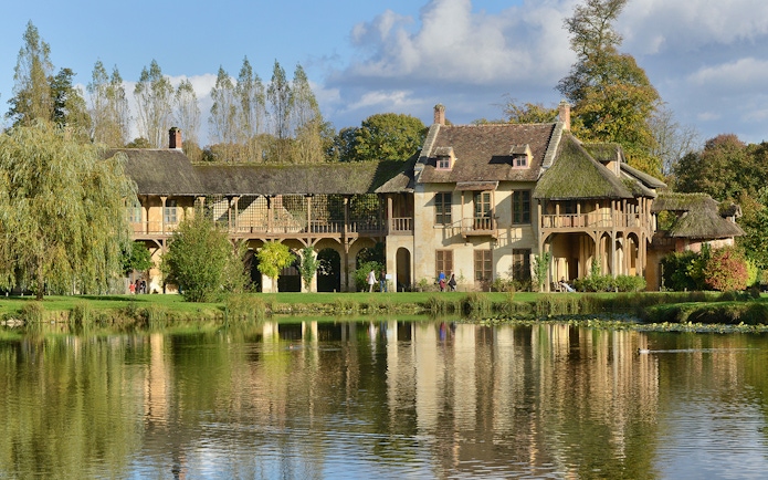 Tourists walking by the lake at Versailles Palace, France.